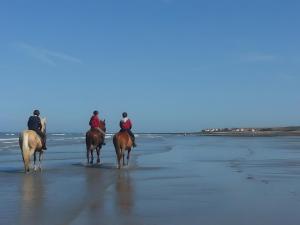 three people riding horses on the beach at La Coccinelle Des Caps in Ambleteuse