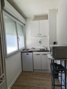 a kitchen with white cabinets and a sink at Studio 3 lits in Saint-Louis