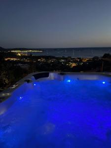 a large blue swimming pool with a view of the ocean at Villasimius Il patio sul porto in Villasimius