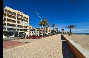 a sandy beach with palm trees and a building at Pasarla rico in Torreblanca