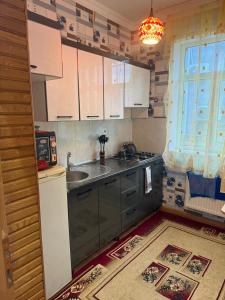 a kitchen with white cabinets and a sink and a window at Gabala mountain house in Gabala