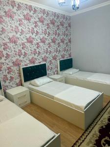 two beds in a room with floral wallpaper at Gabala mountain house in Gabala