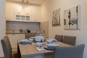 a dining room table with chairs and a kitchen at Lumi Apartment in Podgorica