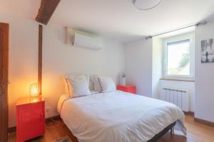 a bedroom with a white bed with a red nightstand and a window at Domaine Cherps Spa - Zen in Vielleségure