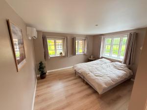 a bedroom with a bed and two windows at Krummeled Rooms & Shelter by the forest in Hasle