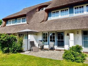 a house with chairs and an umbrella in front of it at Hochstieg Whg 3 in Nieblum