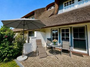 a table with chairs and an umbrella in front of a house at Hochstieg Whg 3 in Nieblum
