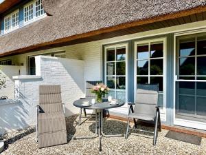 a patio with two chairs and a table with flowers on it at Hochstieg Whg 3 in Nieblum