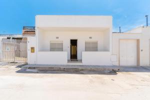 a white house with a door in a parking lot at Baia Di Torre Squillace in Sant'Isidoro