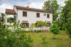 a white house with a yard with trees at Apartman Maria Pia in Lovran