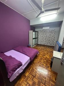a bedroom with a purple bed and a wooden floor at Kapar Cozy Homestay in Kapar