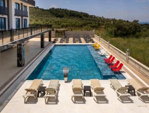 a pool with chaise lounge chairs and a bunch ofvisorvisor at Asil Luxury Boutique in Burhaniye