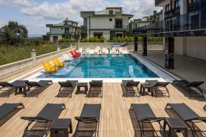 a large swimming pool with chairs and tables on a deck at Asil Luxury Boutique in Burhaniye +12 photos