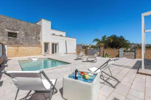 a patio with a table and chairs and a pool at B&B Li Peticurti in Cerfignano