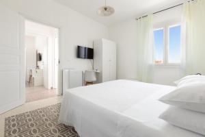 a white bedroom with a white bed and a window at B&B Li Peticurti in Cerfignano