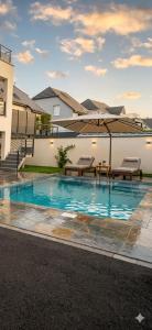 a swimming pool with two benches and an umbrella at Appartement plain-pied en Alsace in Mittelwihr