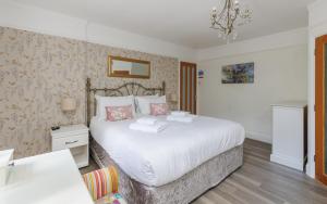a bedroom with a large white bed and a chandelier at Undercliff View - St Lawrence Retreat in Saint Lawrence