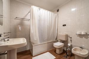 a white bathroom with a toilet and a sink at Guest House Da Mata in Póvoa de Varzim +32 photos