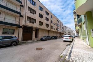 two cars parked on a street next to a building at Guest House Da Mata in Póvoa de Varzim
