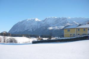 a house in the snow with a mountain in the background at Ferienwohnung Schretthauser in Bad Mitterndorf