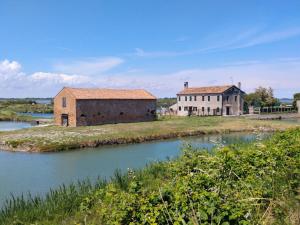 an old house and a building next to a river at Venice Delta Lagoon Apartments in Porto Viro
