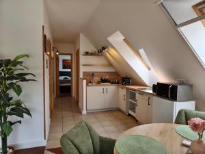 an attic kitchen with white cabinets and a table at Salvia Guesthouse Balatonfüred in Balatonfüred
