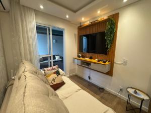 a living room with a couch and a flat screen tv at Apartamento Garden com churrasqueira área Gourmet in Bauru