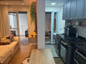 a kitchen and living room with a couch and a table at Apartamento Garden com churrasqueira área Gourmet in Bauru