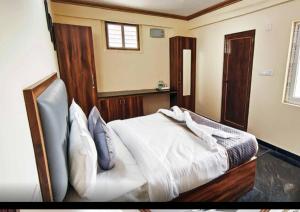 a bedroom with a bed with white sheets and blue pillows at Sri Sai royal suites in Sonda