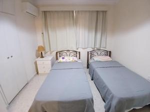 two beds in a small room with a window at Miltos beach House in Larnaca