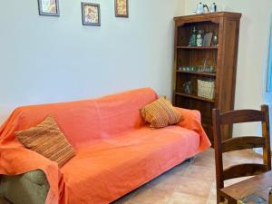 an orange couch in a living room with a book shelf at 4VENTI by LigurianLife in Vallebona