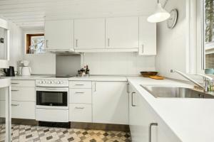 a white kitchen with white cabinets and a sink at Cottage Near Forest And Beach in Glesborg