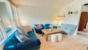 a living room with a blue couch and a table at Cottage Near Forest And Beach in Glesborg +19 photos