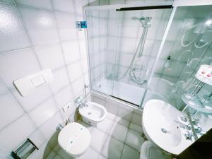 a white bathroom with a toilet and a sink at Hotel Britannia in Genoa +41 photos