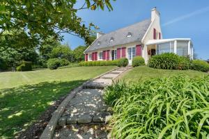 a red and white house with a grass yard at Chambres D'hôtes Kergollay in Lanhouarneau