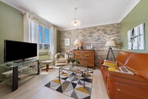 a living room with a leather couch and a tv at Chambres D'hôtes Kergollay in Lanhouarneau