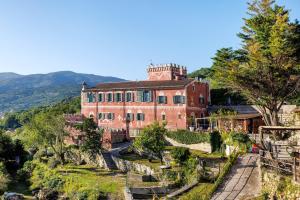a large red brick building on a hill with trees at Villa Piuma in Finale Ligure