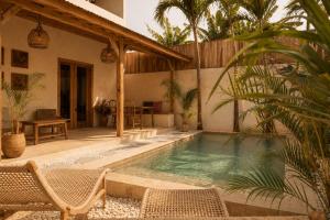 a swimming pool with chairs and a house at Villa Kampung in Gili Islands