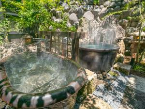 a hot tub in a garden with a fountain at Kirishima Kokusai Hotel in Kirishima