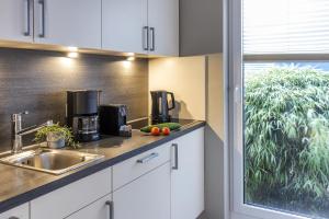 a kitchen with white cabinets and a sink and a window at Pier17 Appartement 2 in Borkum +9 photos