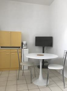 a kitchen with a table and two chairs and a tv at Acionna Résidence Studio 30 M² in Bourbonne-les-Bains