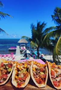 three hot dogs on a table next to the beach at Barefoot Beach Belize in Caye Caulker