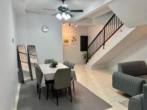 a dining room with a table and chairs and a staircase at Khaeel Homestay in Ipoh