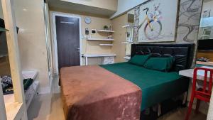 a bedroom with a large bed with a green blanket at Student Castle Apartement by Dev's Room in Seturan