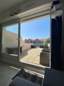 a room with a large window with a view of a patio at Le Sunny Hardelot in Neufchâtel-Hardelot