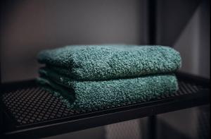 a pile of green towels sitting on a shelf at 1 Le Cocon Mosaïque Centre-ville in Ernée +25 photos