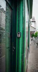 a green door with a sign on the side of a building at 1 Le Cocon Mosaïque Centre-ville in Ernée