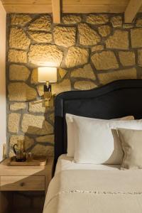 a bedroom with a bed and a stone wall at Meteora boutique villa A in Kalabaka