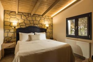a bedroom with a bed and a stone wall at Meteora boutique villa A in Kalabaka