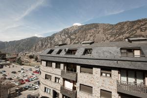 a building with a parking lot and mountains in the background at Outdoor Apartaments - Spot in Andorra la Vella